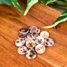 Load image into Gallery viewer, "Collection of round buttons on a wooden surface with leaves in the background," - Down to Earth.