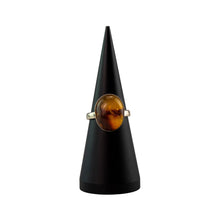 Load image into Gallery viewer, "Amber Oval Ring with a brown gemstone on a black cone-shaped stand against a white background," - Down to Earth.