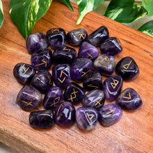 Load image into Gallery viewer, "Amethyst runes on a wooden surface with green leaves in the background," - Down to Earth.