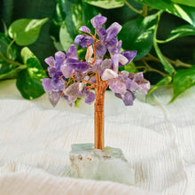 Load image into Gallery viewer, Decorative crystal tree with amethyst stones on a green base, surrounded by green leaves.