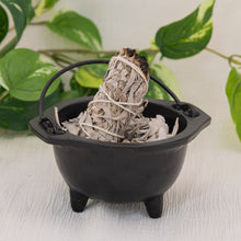 Load image into Gallery viewer, Cast Iron 6" Plain Cauldron filled with sage with a white background and leaves in the foreground - Down To Earth