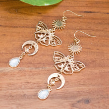 Load image into Gallery viewer, Celestial Sun & Moon Butterfly Earrings top down displayed on a styled background - Down To Earth