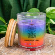 Load image into Gallery viewer, "Earth's Elements Wellness Chakra Crystal Candle on a wooden plank with green foliage in the background," - Down to Earth.