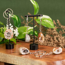 Load image into Gallery viewer, Assorted Crystal Geode Keychain displayed on a wooden surface with a colorful background third angle - Down to Earth