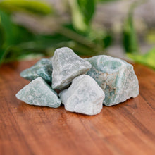 Load image into Gallery viewer, Green Aventurine crystals on a wooden surface with blurred greenery in the background - Down to Earth