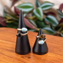 Load image into Gallery viewer, "Two black cone-shaped ring stands with rings on a wooden surface with a blurred plant background," - Down to Earth.
