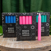 Load image into Gallery viewer, "Three packs of Magic Spell Candles in the variations wisdom, friendship, and luck on a wooden plank with a green background," - Down to Earth.