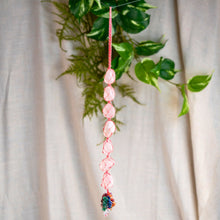 Load image into Gallery viewer, "Rose Quartz Car Mobile with Chakra Beads in front of a beige background with green foliage," - Down to Earth.