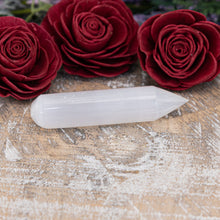 Load image into Gallery viewer, Selenite Point Wand sitting on a tray with flowers in the foreground - Down To Earth