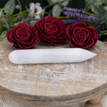 Load image into Gallery viewer, Selenite Point Wand sitting on a tray with flowers in the foreground - Down To Earth