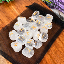 Load image into Gallery viewer, "Tumbled Clear Quartz Rune Set on a black organza bag with foliage in the background," - Down to Earth.
