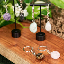 Load image into Gallery viewer, Tumbled Crystal Keychains displayed on a colorful background close up angle - Down to Earth