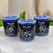 Load image into Gallery viewer, "Three blue candles labeled 'Wealth Water' on a marble surface with a neutral background," - Down to Earth.