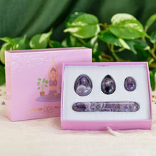 Load image into Gallery viewer, "A four-piece amethyst yoni egg set in a light pink box, propped up by the lid that has a graphic of a woman practicing yoga on it," - Down to Earth.