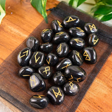 Load image into Gallery viewer, "Black Obsidian Rune Set on top of a black organza bag with green foliage in the background," - Down to Earth.