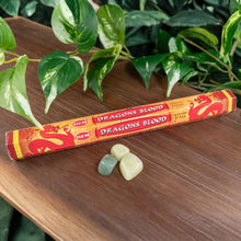 Load image into Gallery viewer, "HEM Dragon's Blood incense stick pack on a wooden surface with green leaves in the background," - Down to Earth.