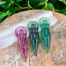 Load image into Gallery viewer, "Three Fluorite Goddess Statues leaning on Selenite wands with green foliage in the background," - Down to Earth.