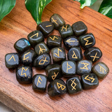 Load image into Gallery viewer, "Close-up of a Labradorite Rune Set that has 25 pieces on a wooden plank with green foliage in the background," - Down to Earth.