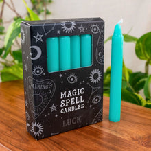 Load image into Gallery viewer, "Green Luck Magic Spell Candles on a wooden base with green foliage in the background," - Down to Earth.