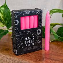 Load image into Gallery viewer, "Pink candles with a 'Magic Spell Candles' packaging on a wooden surface with plants in the background." - Down to Earth.