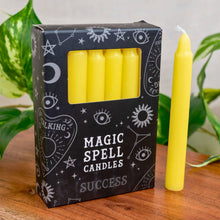 Load image into Gallery viewer, "Box of yellow 'Magic Spell Candles' with decorative symbols on a wooden surface," - Down to Earth.