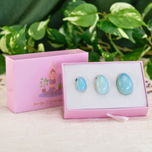 Load image into Gallery viewer, "A three-piece opalite yoni egg set within a light pink box, propped up against its lid with a greenery background," - Down to Earth.