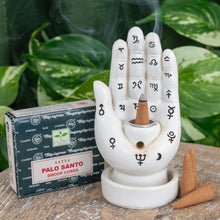 Load image into Gallery viewer, "Single package of Palo Santo Satya Dhoop Cones next to a Palmistry Incense Burner on a wooden plank with green foliage in the background," - Down to Earth.