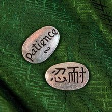 Load image into Gallery viewer, "Two oval metal tokens with engraved text on a green textured background," - Down to Earth.