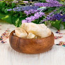 Load image into Gallery viewer, "Wooden bowl overflowing with pieces of natural raw citrine with a floral background," - Down to Earth.