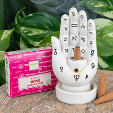 Load image into Gallery viewer, "Single package of Satya Rose Dhoop Cones next to a Palmistry Incense Burner on a wooden plank with green foliage in the background," - Down to Earth.