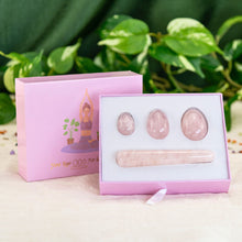 Load image into Gallery viewer, "An open light pink box propped up against its lid, showcasing a four-piece set of rose quartz yoni eggs. The lid has a graphic of a woman practicing yoga with two plants behind her," - Down to Earth.