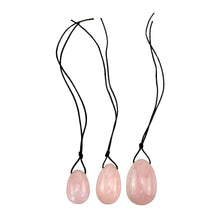 Load image into Gallery viewer, "Three rose quartz yoni eggs with black string tied to their tops," - Down to Earth.