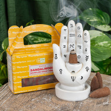 Load image into Gallery viewer, "Single package of Sandalwood Satya Backflow Dhoop Cones on a wooden plank with green foliage in the background," - Down to Earth.