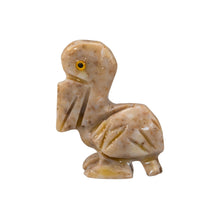 Load image into Gallery viewer, "Left side of a small stone sculpture in the shape of a pelican with yellow eyes against a white background," - Down to Earth.