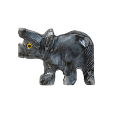 Load image into Gallery viewer, "Left side of a triceratops stone carving that has yellow eyes against a white background," - Down to Earth.