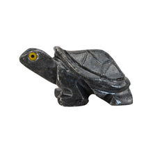 Load image into Gallery viewer, "Left side of a stone carved animal in the shape of a tortoise that has yellow eyes and is against a white background," - Down to Earth.