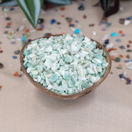 Small wooden bowl filled with Amazonite Crystal Chips on a beige surface with scattered stones around - Down To Earth