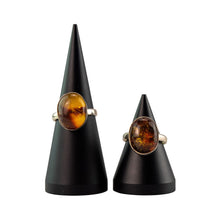 Load image into Gallery viewer, "Two Amber Oval Rings on black stands with a white background," - Down to Earth.
