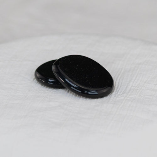 Black Tourmaline Palm Stone on a white cloth - Down to Earth 