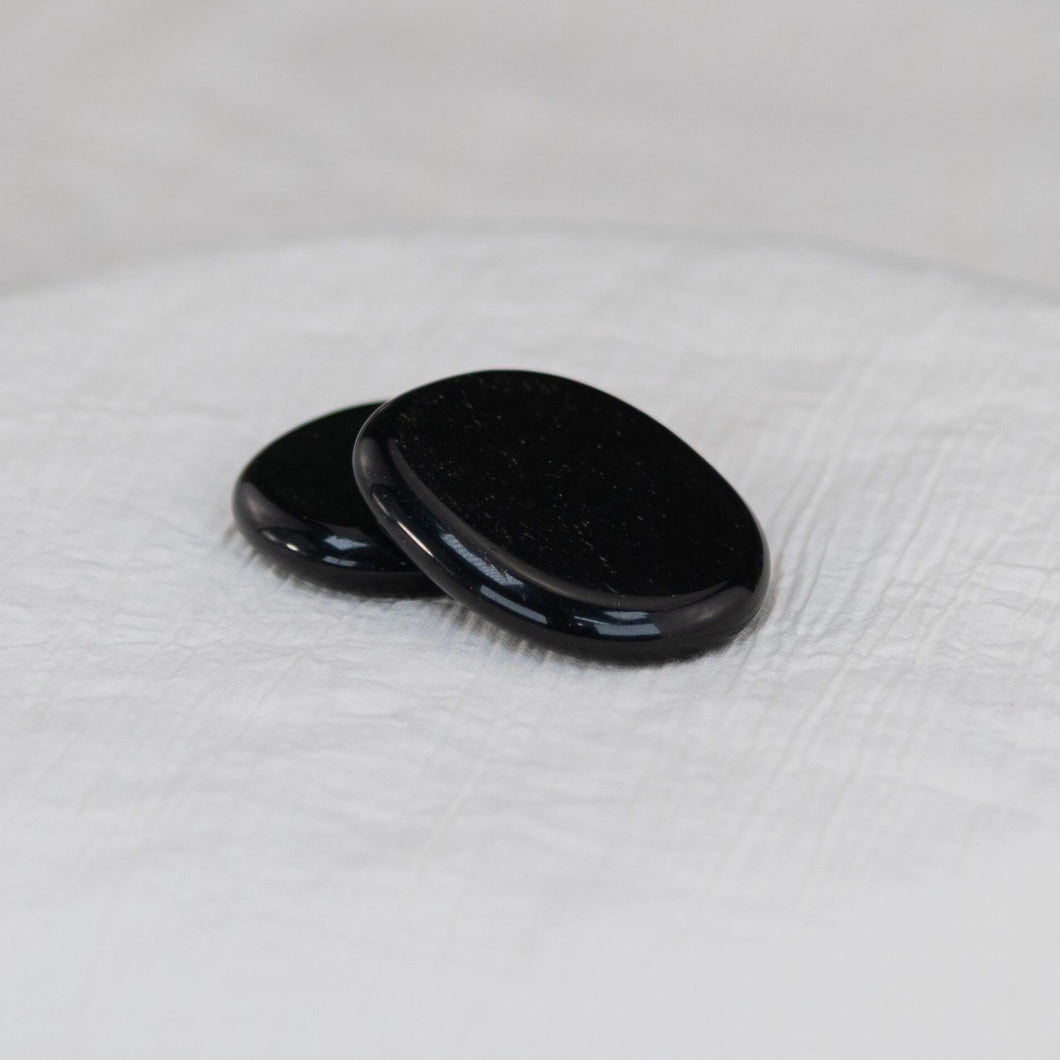 Black Tourmaline Palm Stone on a white cloth - Down to Earth 