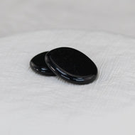 Black Tourmaline Palm Stone on a white cloth - Down to Earth 