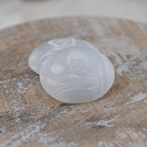 Buddha Engraved Selenite Palm Stones on a wooden surface - Down to Earth 