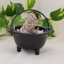 Load image into Gallery viewer, Cast Iron 6&quot; Plain Cauldron filled with sage with a white background and leaves in the foreground - Down To Earth
