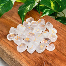 Load image into Gallery viewer, "Clear Quartz Rune Set on a wooden base with green leaves in the background," - Down to Earth.
