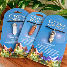 Load image into Gallery viewer, "Three Crystal Energy product packages on a wooden surface with greenery in the background," - Down to Earth.
