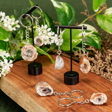Load image into Gallery viewer, Assorted Crystal Geode Keychain displayed on a wooden surface with a colorful background - Down to Earth
