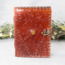 Load image into Gallery viewer, Evil Eye Leather Journal front facing with plants displayed on a styled background - Down To Earth
