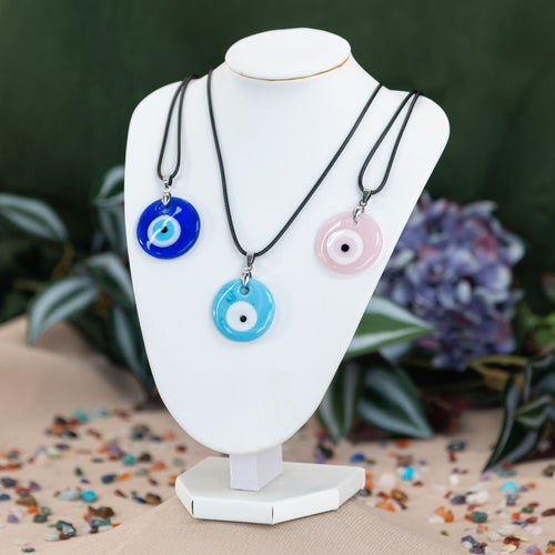 Three evil eye necklaces on a white mannequin neck against a green background - Down to Earth