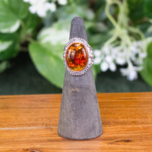 Load image into Gallery viewer, Honey Amber Oval Ring front facing with plants displayed on a styled background- Down To Earth
