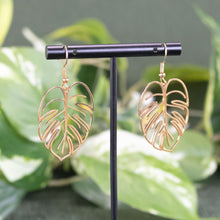 Load image into Gallery viewer, Monstera Leaf Earrings on a jewelry stand displayed on a styled background - Down to Earth
